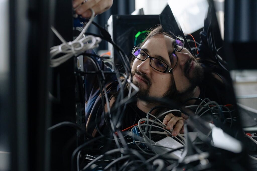 pexels-photo-6804585 Employee Working Through the Tangle of Cables Behind the Computer